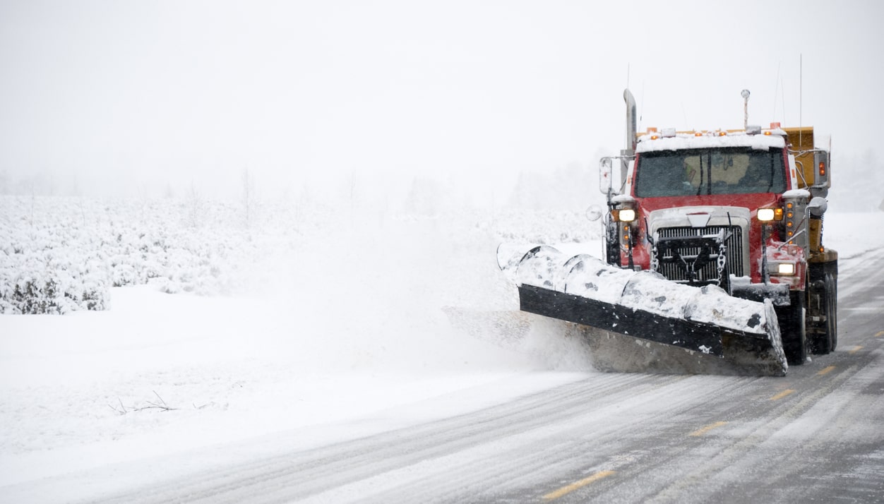 Snow plow pushing snow on road during severe winter weather