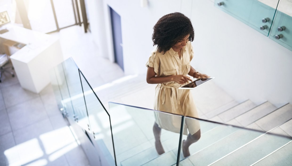 Employee walking up escalator looking at smartphone connected to business WiFi