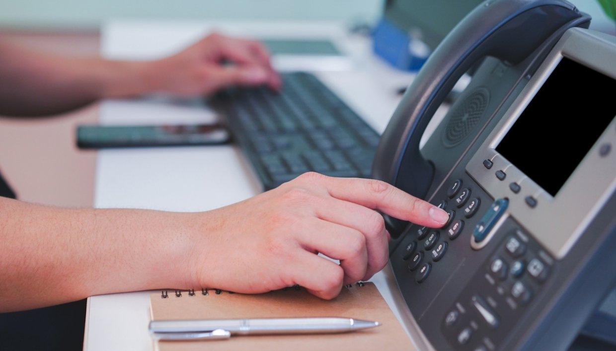 An employee using a phone to check business voicemail