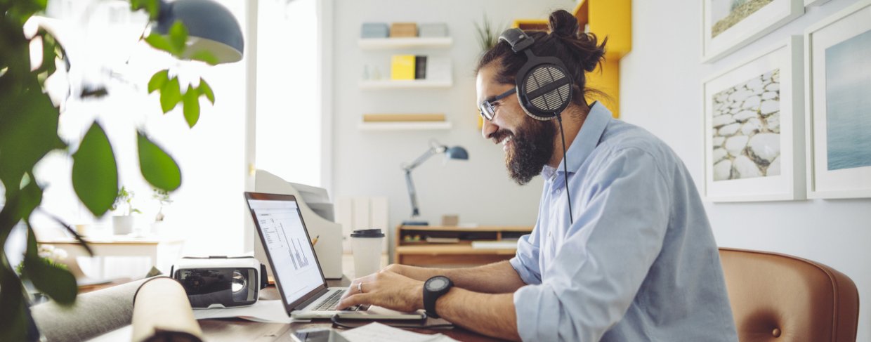Man working from home on his laptop with headphones