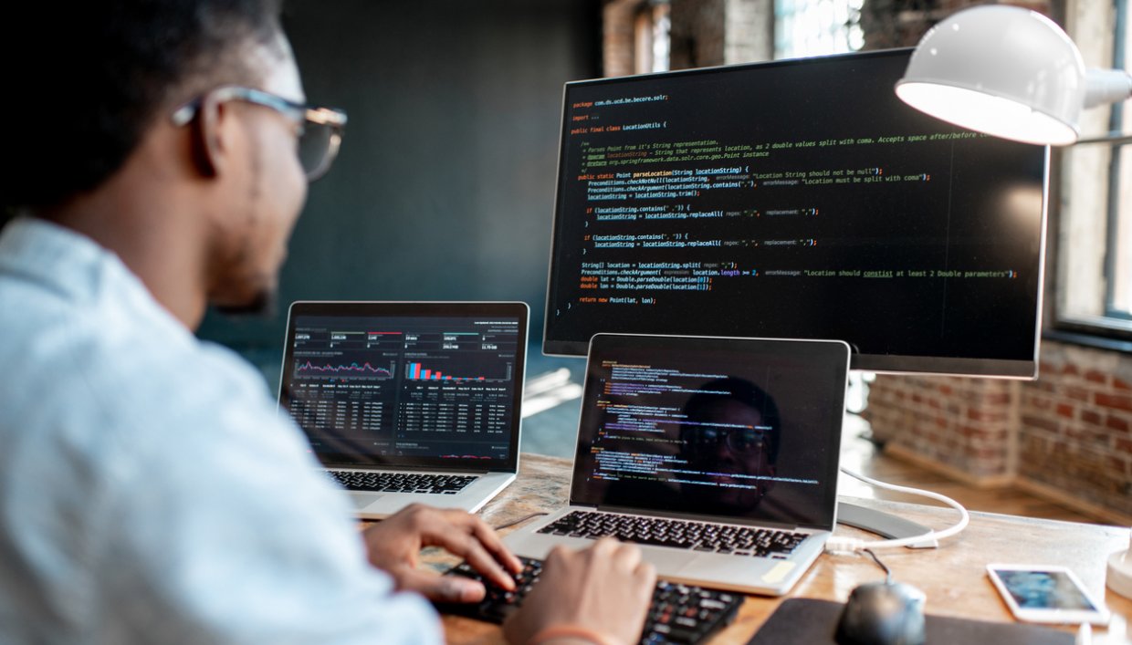 Man working on three computers at his desk