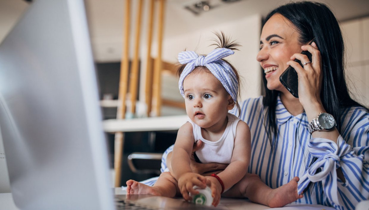 Woman on phone while working from home with baby on lap