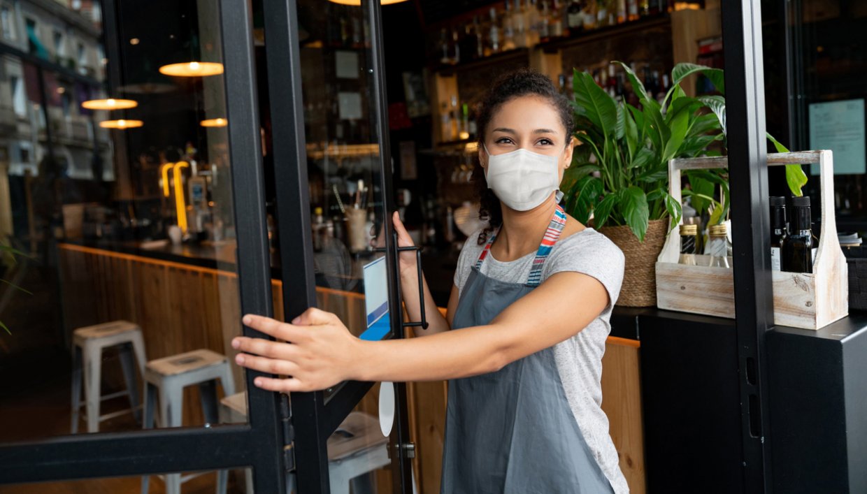 Business owner wearing mask standing in doorway to business