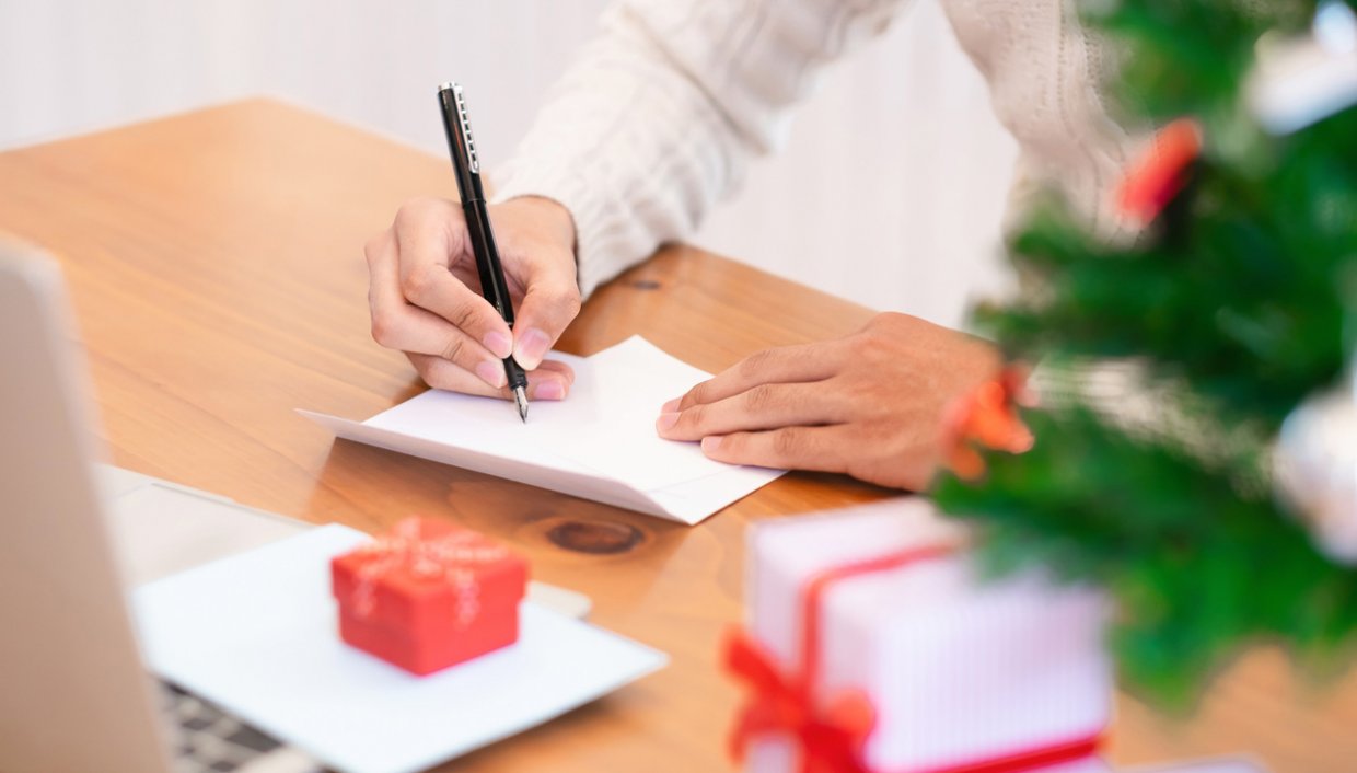 Business owner writing thank-you card to customer over holiday season