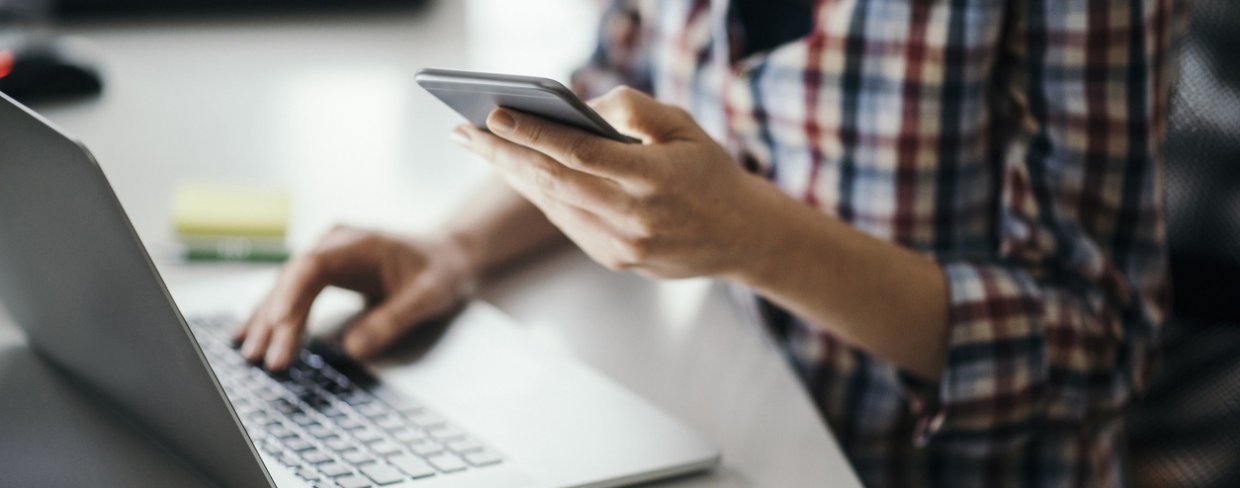 Person looking at computer and mobile phone at the same time