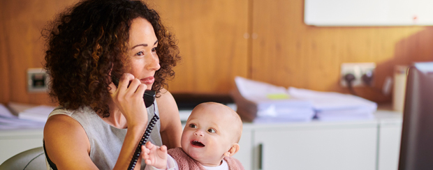Business owner holding baby while on phone