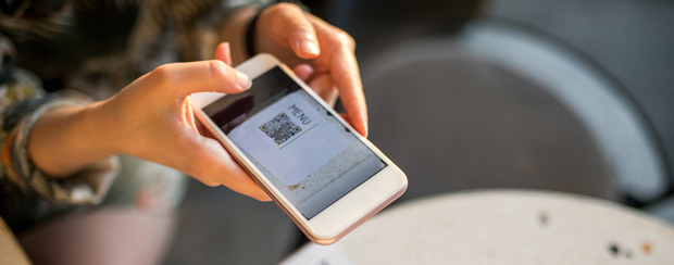 Person using smartphone to scan QR code at business