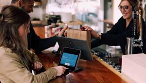 Customer using payment processing tablet at small business