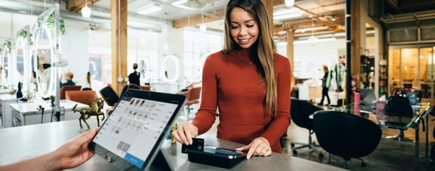 Customer swiping credit card at payment terminal in business