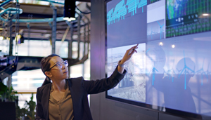 Businesswoman pointing at a large screen with data on it