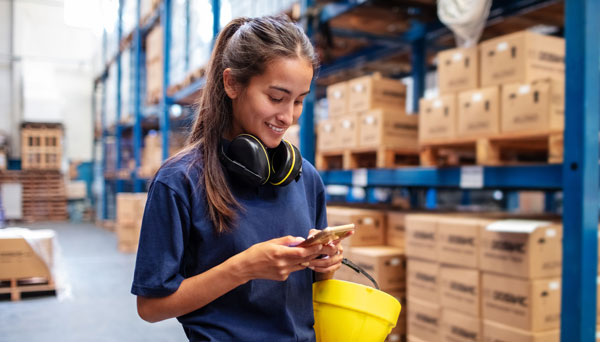 Small business employee using business mobile phone in warehouse